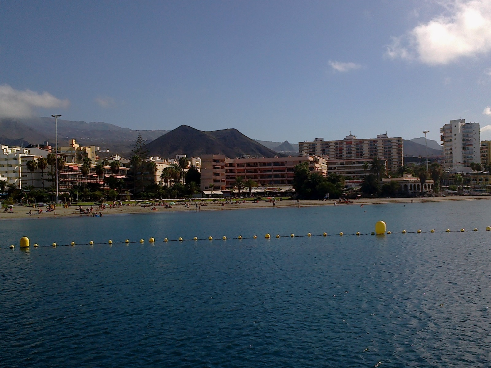 Playa de Los Cristianos beach in Tenerife, featuring a sandy shoreline with calm water conditions