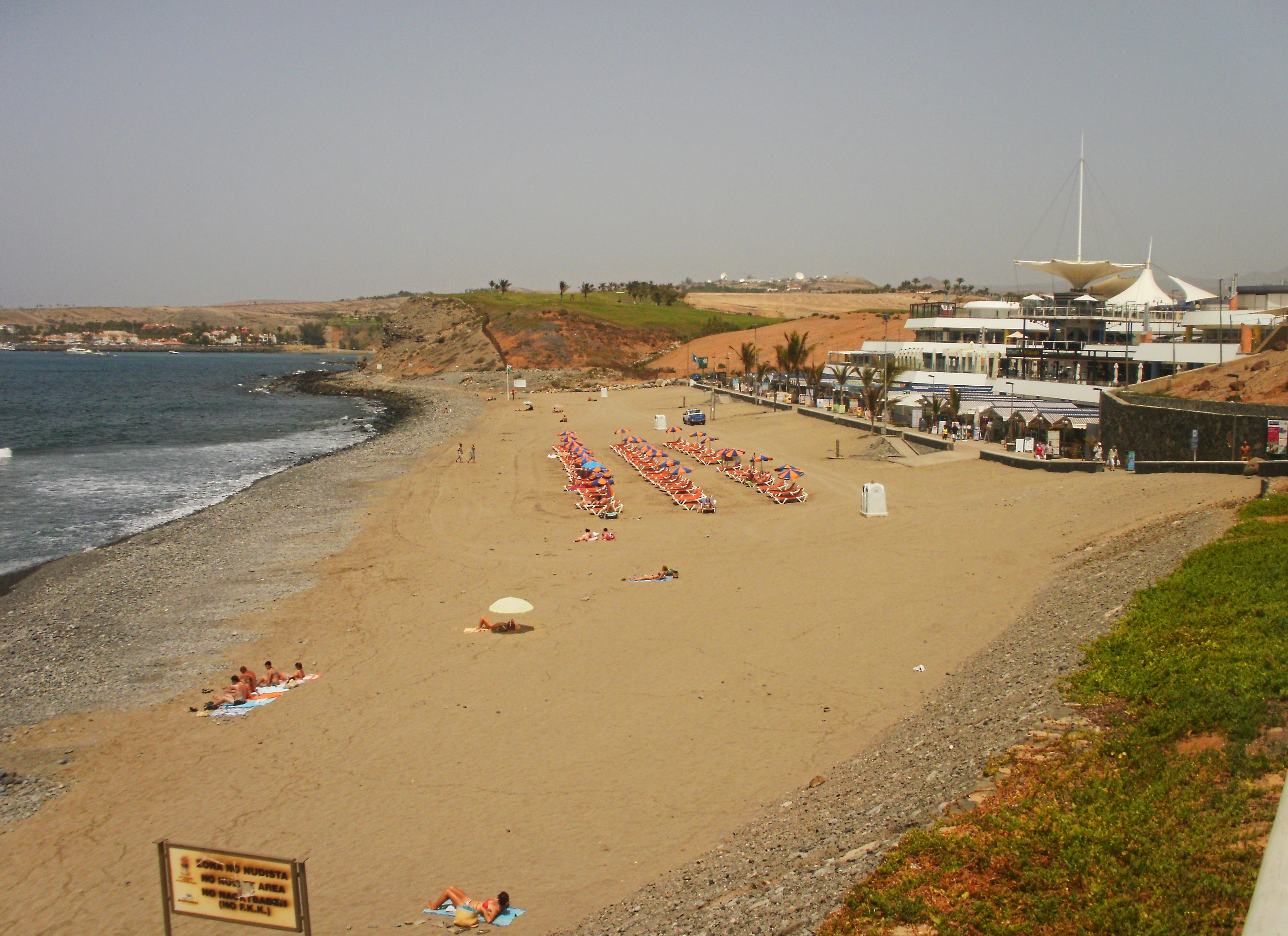 Playa Meloneras beach in Gran Canaria, featuring a sandy shoreline with calm water conditions
