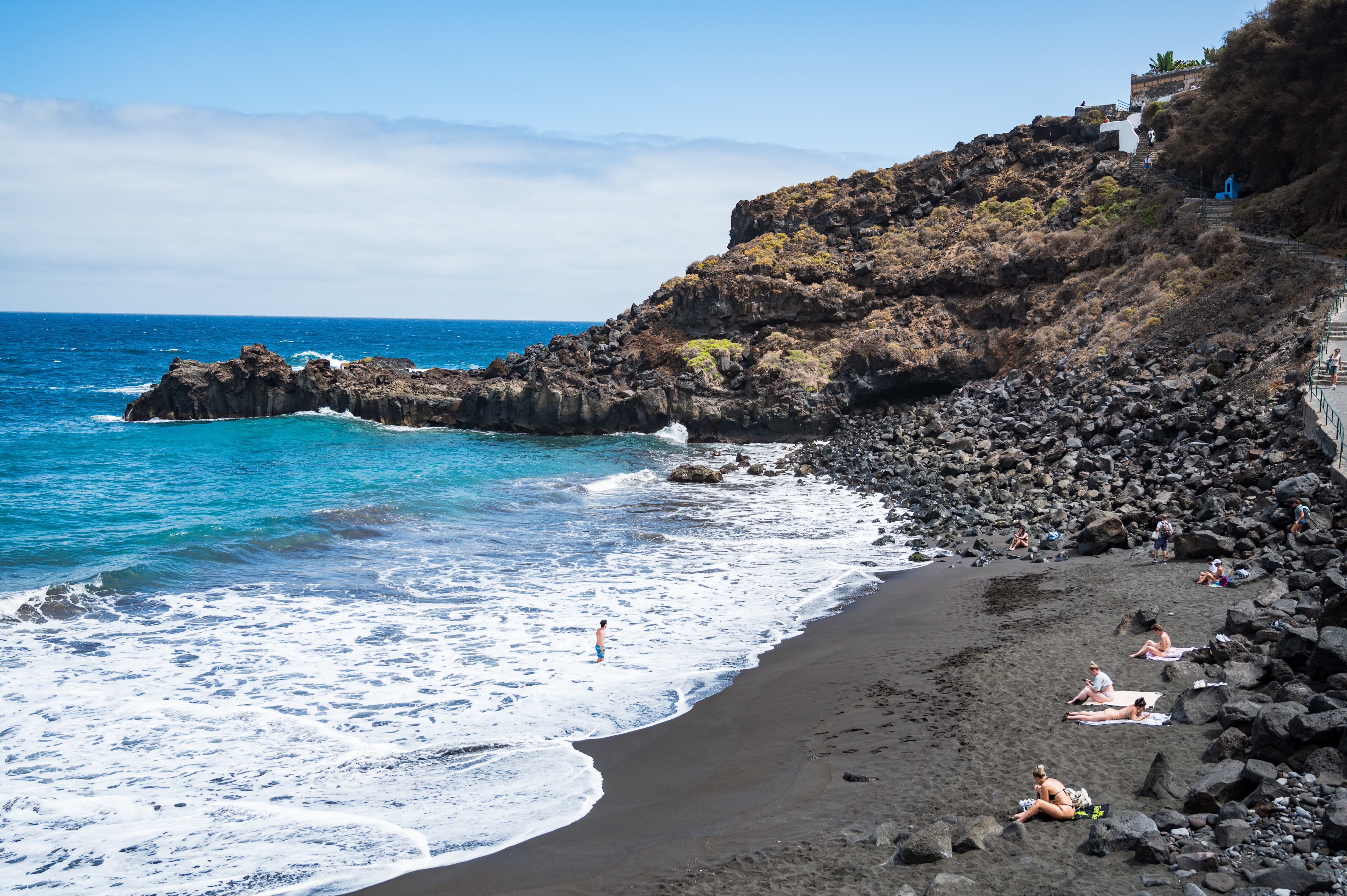 Playa Bollullo beach in Tenerife, featuring a sandy shoreline with surfable water conditions